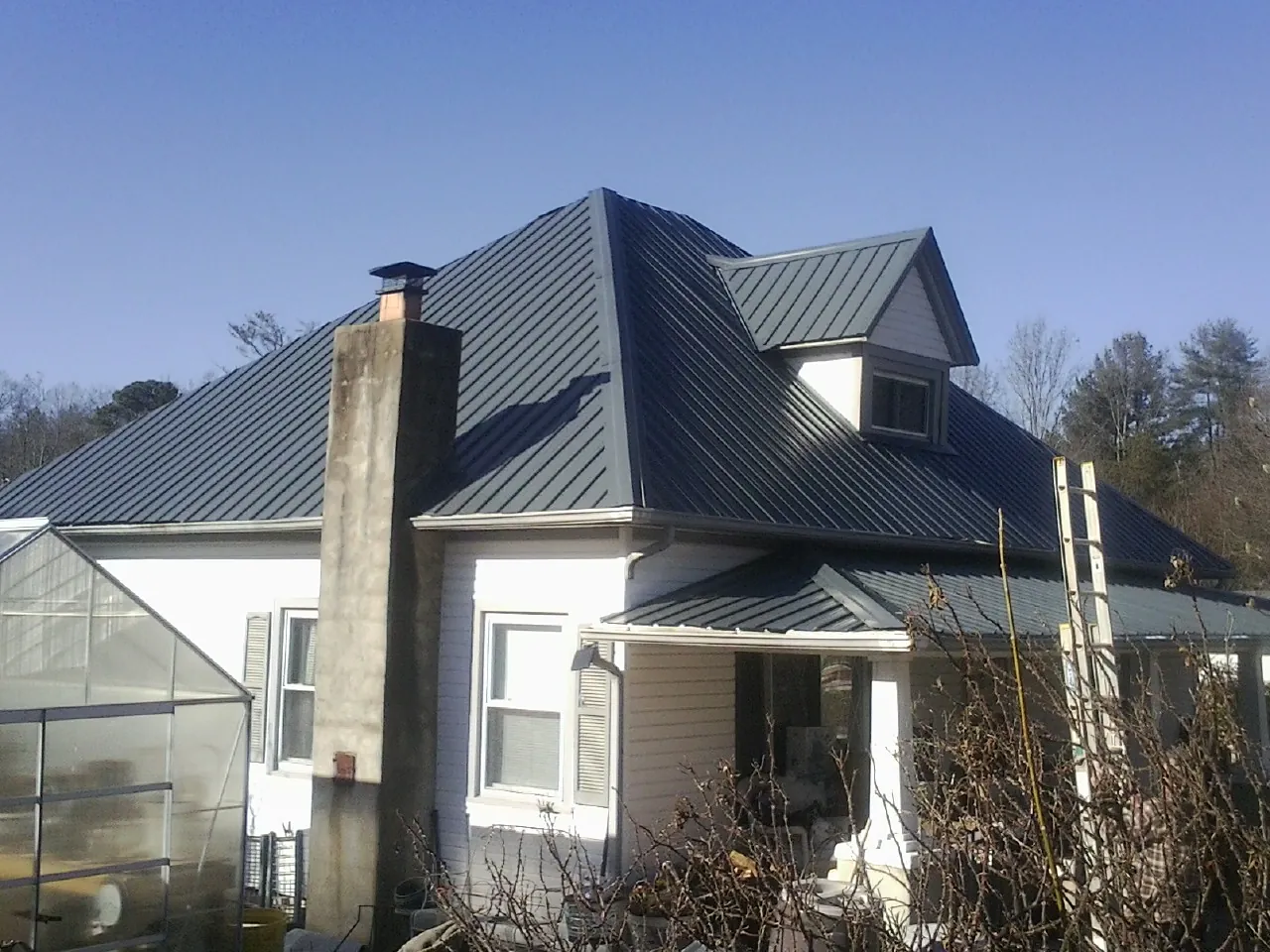 Dark blue standing seam metal roof on a white farmhouse with dormer — Slate & Tile Roof Repair by Roofing Brothers in Ulster Park