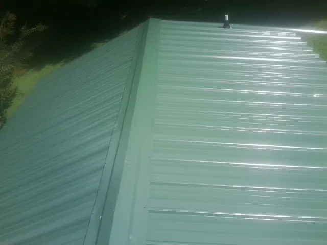 New green metal panels meeting at the ridge of a roof — Flat Roof Repair work by our crew in Ulster Park