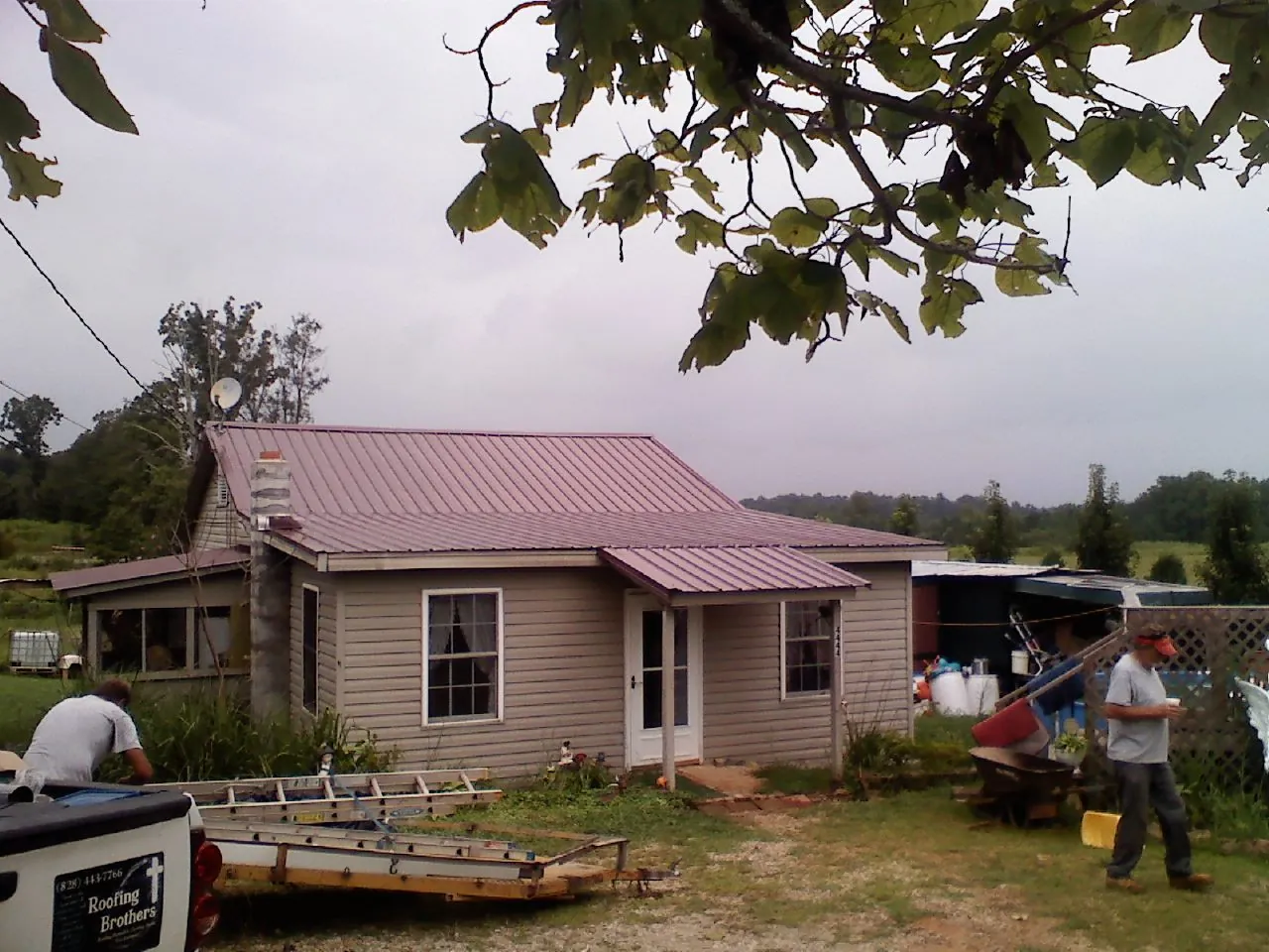 Crew finishing a mauve metal roof on a small farmhouse in Ulster Park
