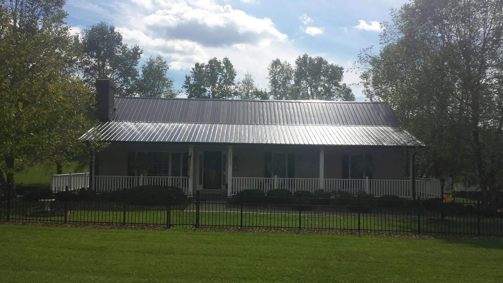Gray metal roof on a brick ranch with a full width front porch — Gutter Guard Installation work by our crew in Ulster Park