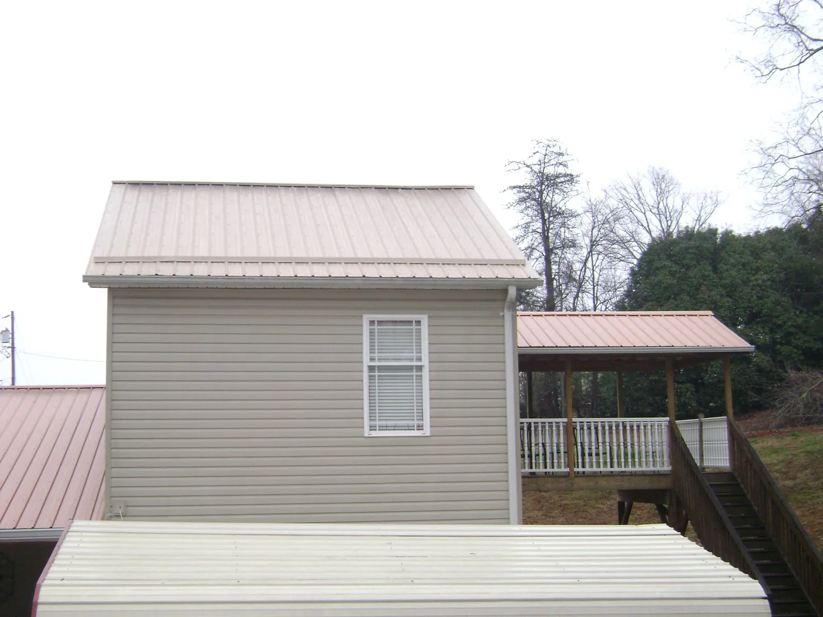 Tan metal roofs on a two story addition and attached porch, from a Roof Replacement job in Ulster Park