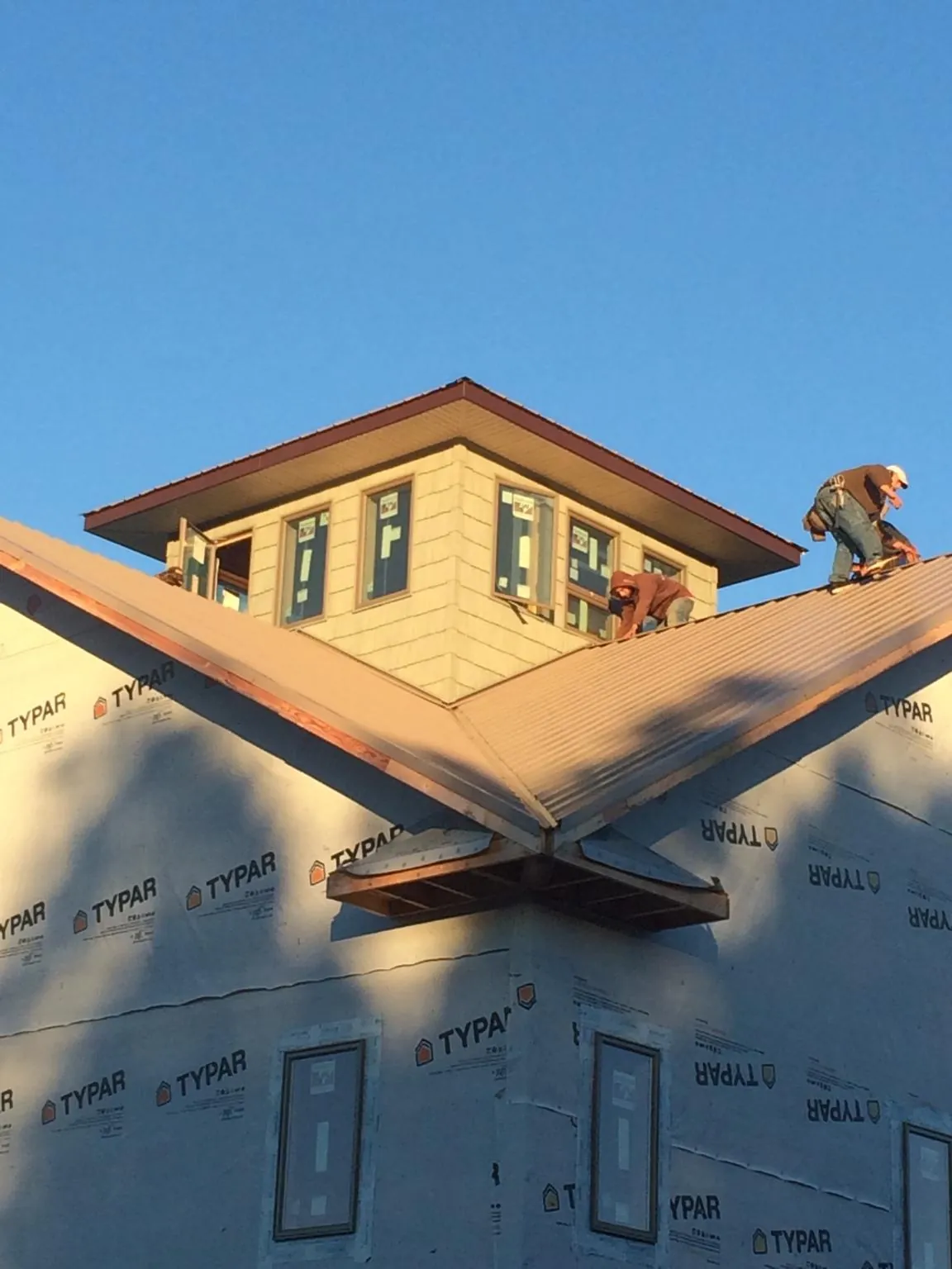 Roofers working around a rooftop cupola on a new metal roof at sunset — Roof Waterproofing in Ulster Park by Roofing Brothers